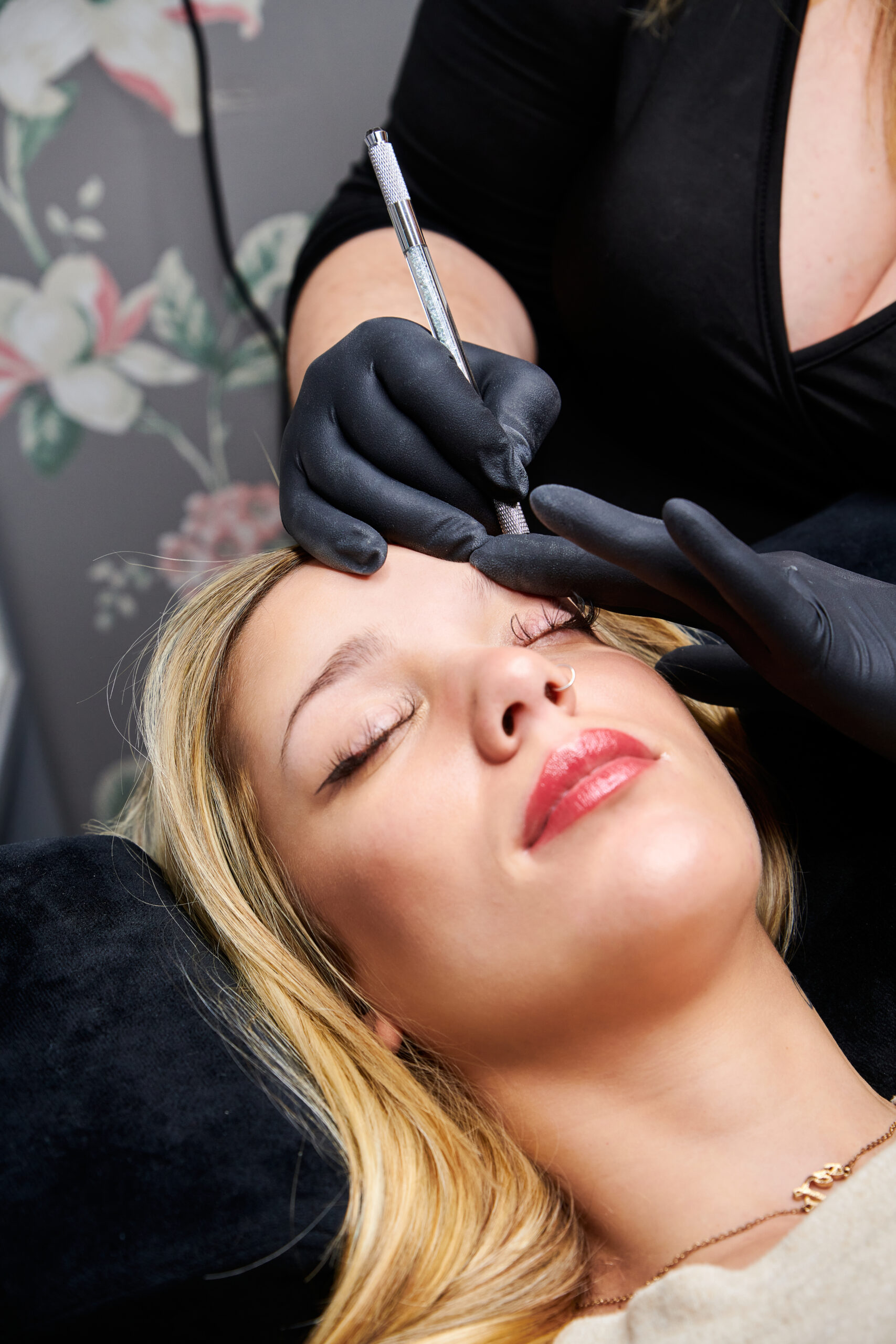 Vertical shot of a female getting her eyebrows fixed by a professional makeup artist